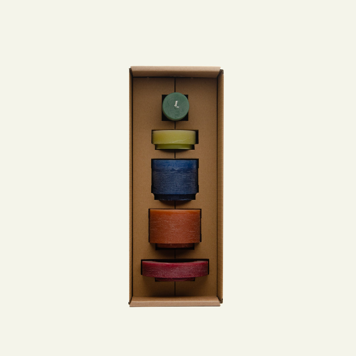 Een set van vijf kaarsen in verschillende kleuren en formaten, netjes verpakt in een kartonnen doos met op maat gemaakte vakken. De kaarsen zijn groen, geel, blauw, bruin en rood en zijn gestapeld in een verticale opstelling.
