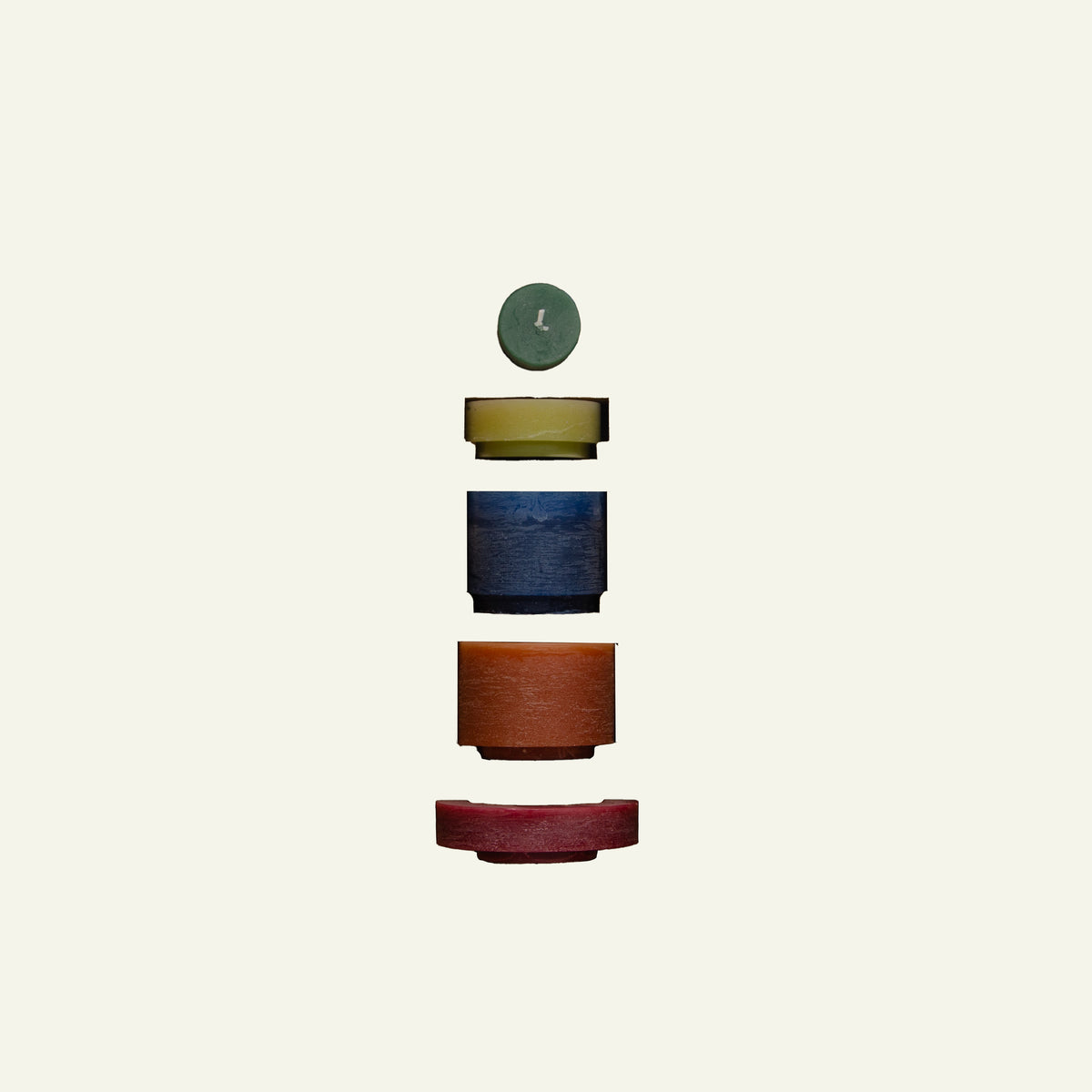 Een minimalistische compositie van vijf verschillende kaarsen, gestapeld in een zwevende opstelling tegen een lichte achtergrond. De kaarsen variëren in kleur, waaronder groen, geel, blauw, oranje en rood, en verschillen in grootte en vorm.